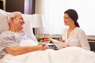 Female Doctor Talking To Senior Male Patient In Hospital Bed